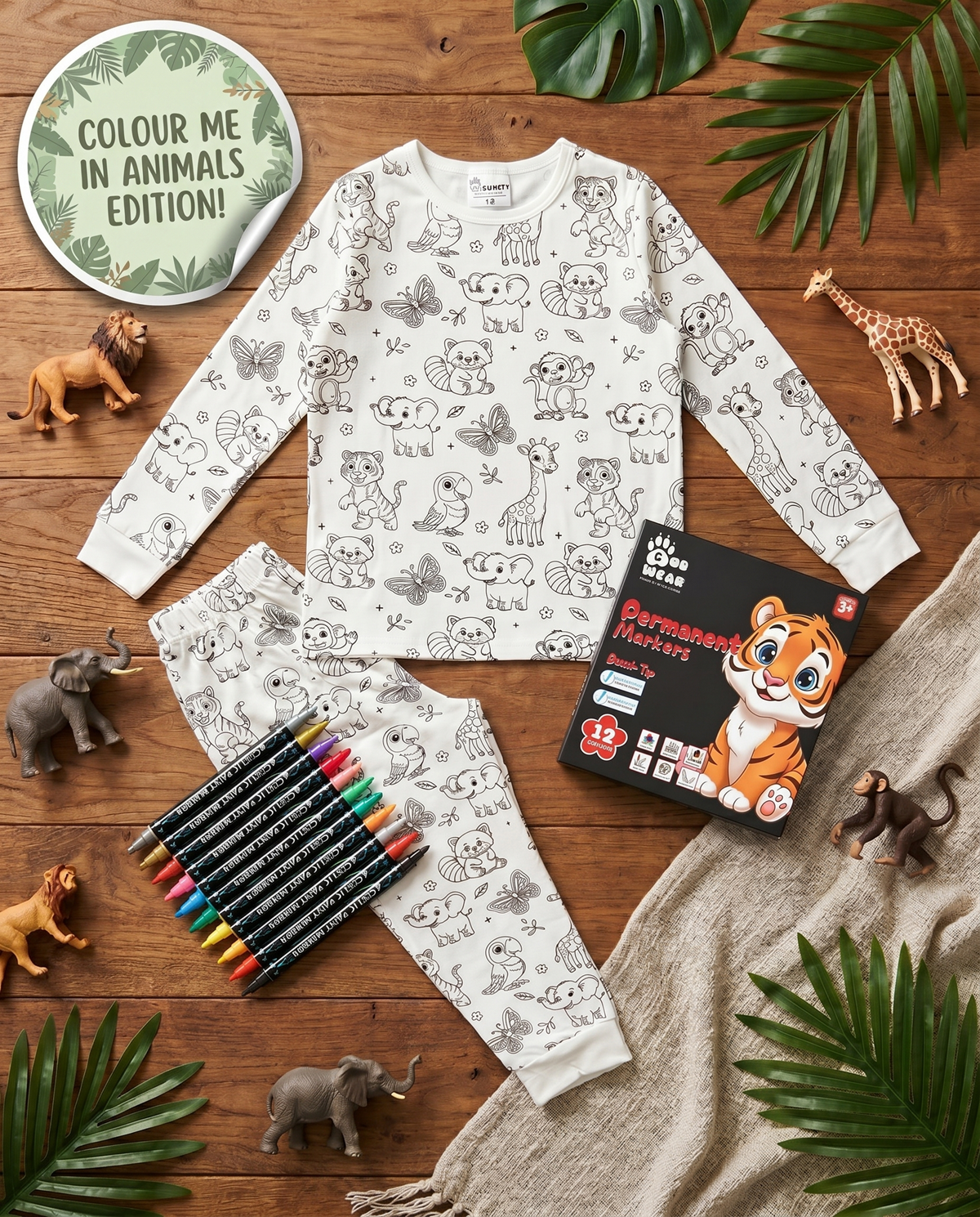 Animal colour-in pyjama set with washable fabric pens laid out on a wooden table.