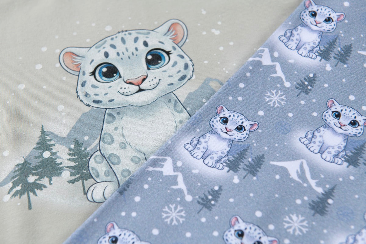 Close-up of blue snow leopard Christmas pyjama fabric showing detailed snow leopard print and soft cotton material.