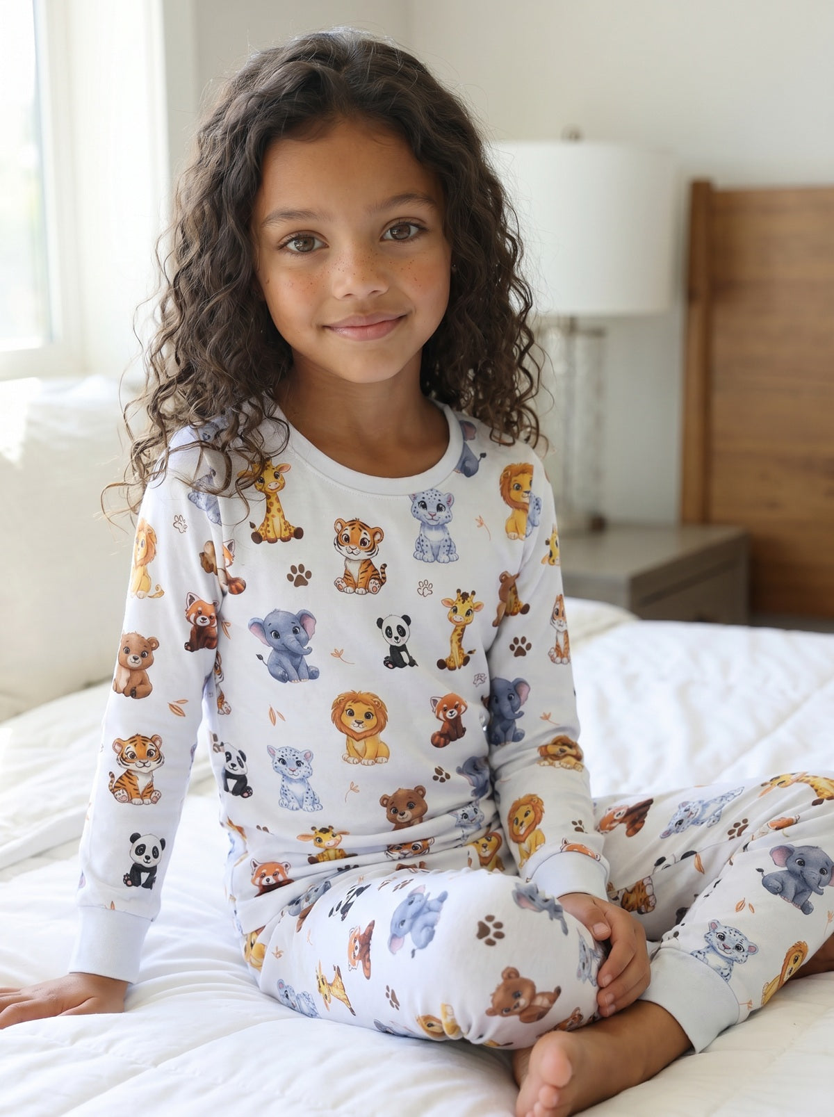 Young girl relaxing on a bed wearing premium jungle animal cotton pyjamas with safari animal print.