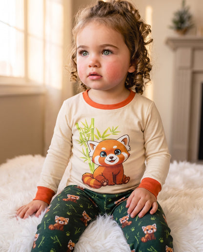 Toddler wearing Red Panda cotton pyjamas sitting in a warm home setting