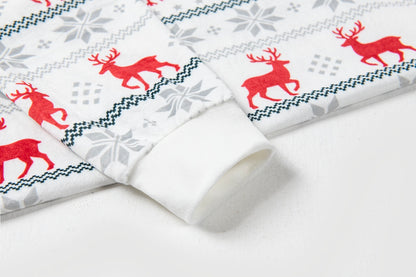 A close-up of a white fabric product, likely a long-sleeve top or garment, featuring a festive Christmas pattern with red reindeer, gray snowflakes, and dark blue geometric borders.