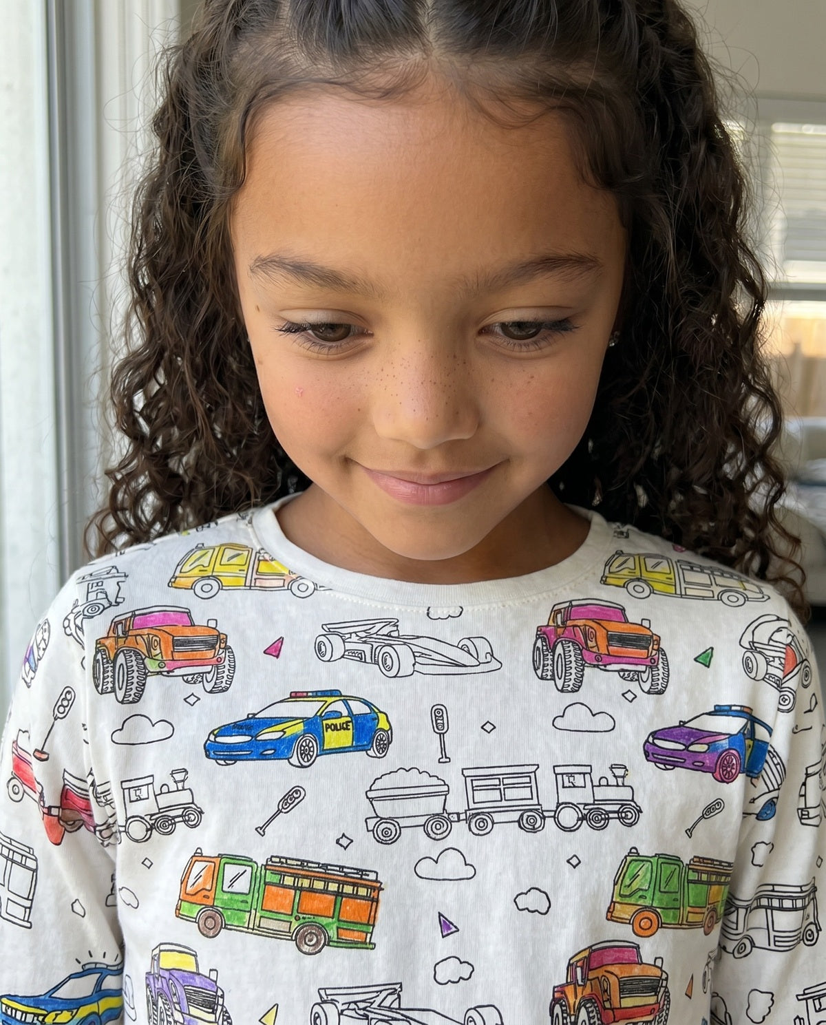 Young girl wearing personalised Vehicles Colour-In Pyjamas decorated with fabric pens.